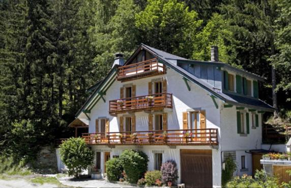 ein großes weißes Haus mit einem Balkon und Bäumen in der Unterkunft White Chalet in Chamonix-Mont-Blanc