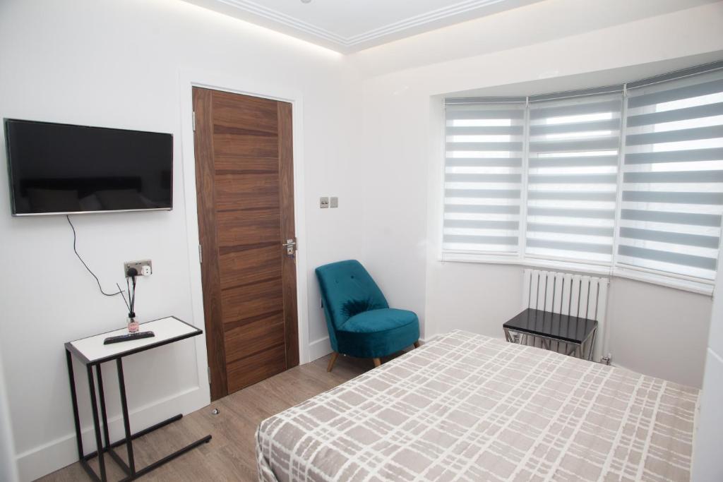 a bedroom with a bed and a blue chair at Goldbeaters House in Edgware