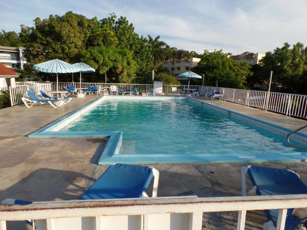 a large swimming pool with chairs and an umbrella at Sky Club @ Montego Bay Club Resort in Montego Bay