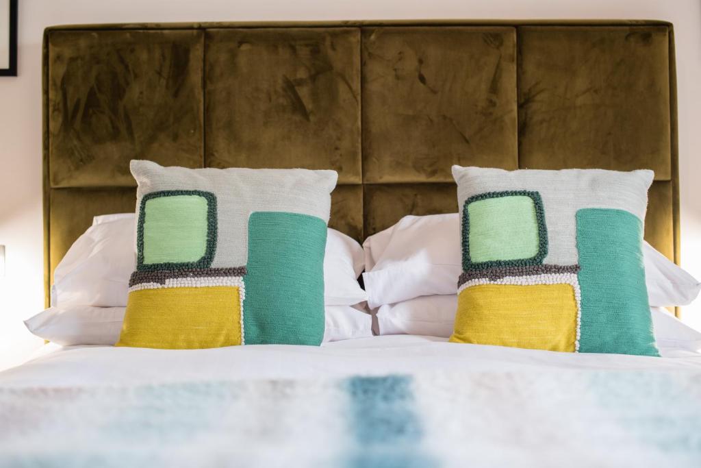 a bed with green and yellow pillows on it at The Hafod in Devils Bridge