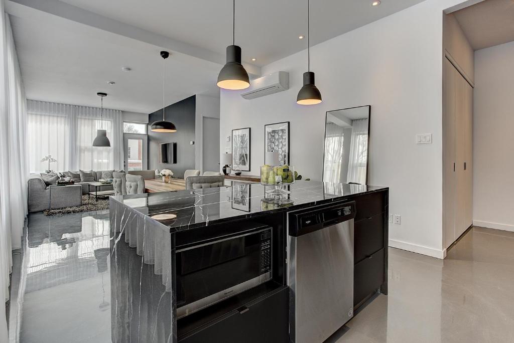 een keuken met zwart-witapparatuur en een woonkamer bij Les Lofts du Centre by Simplissimmo in Montreal