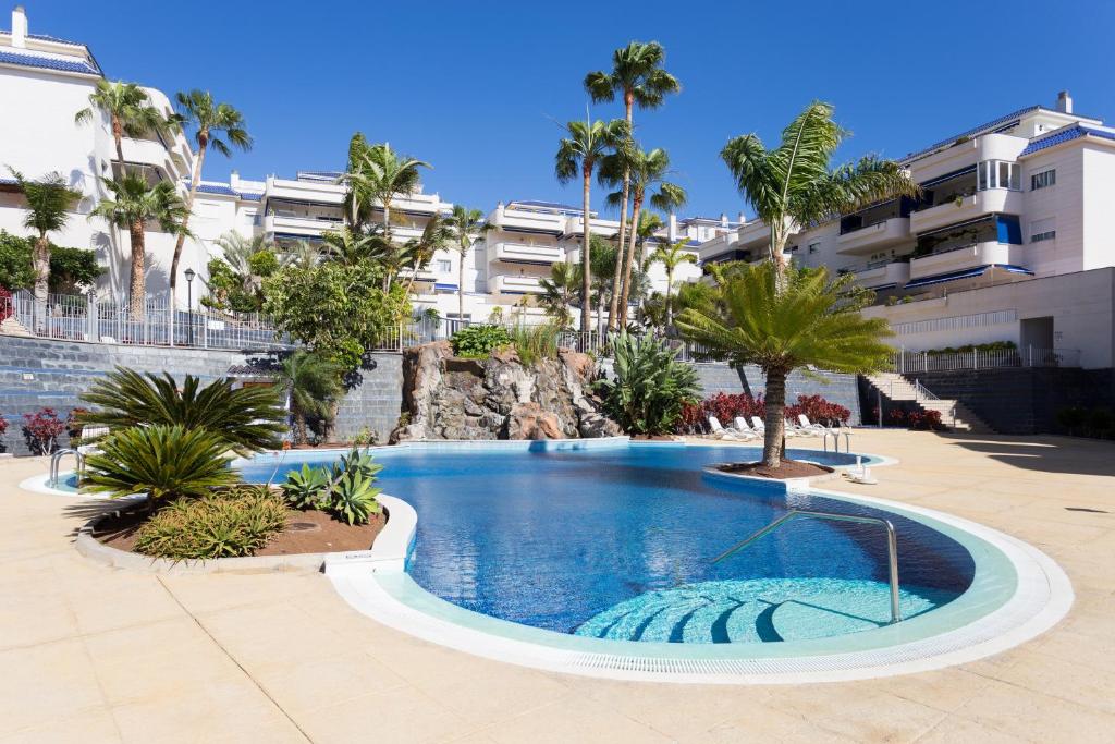 een zwembad in een resort met palmbomen en gebouwen bij El Ancla in Los Cristianos