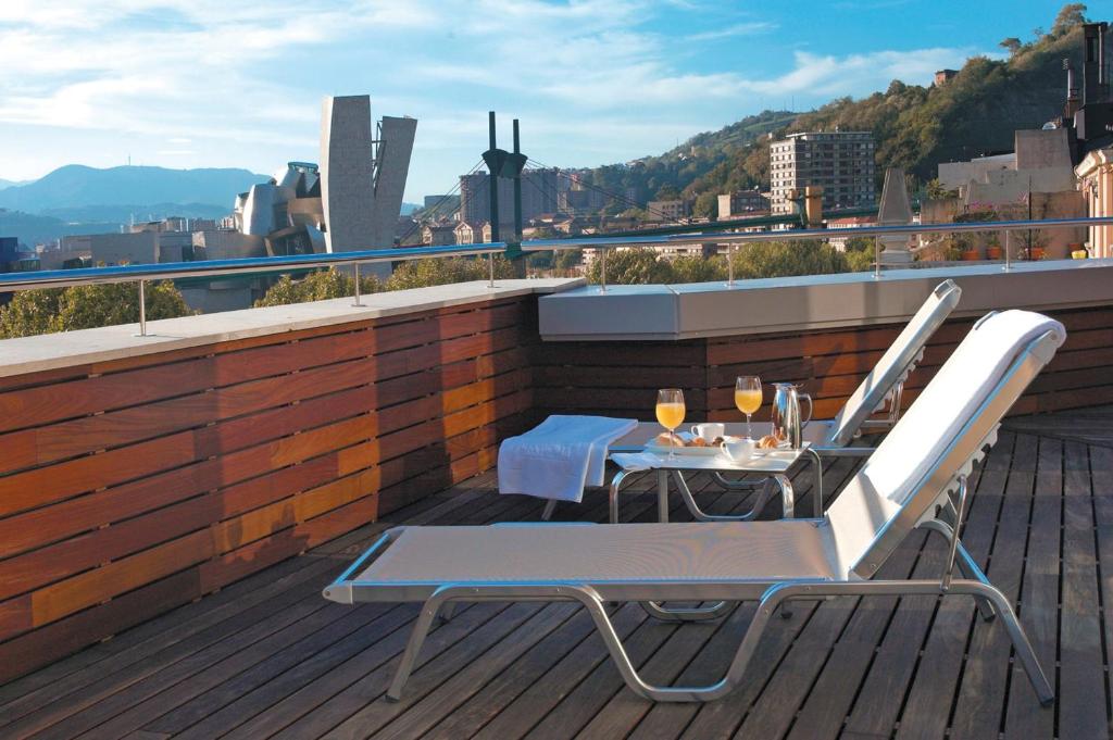 a patio with a table and chairs on a roof at Hesperia Bilbao in Bilbao