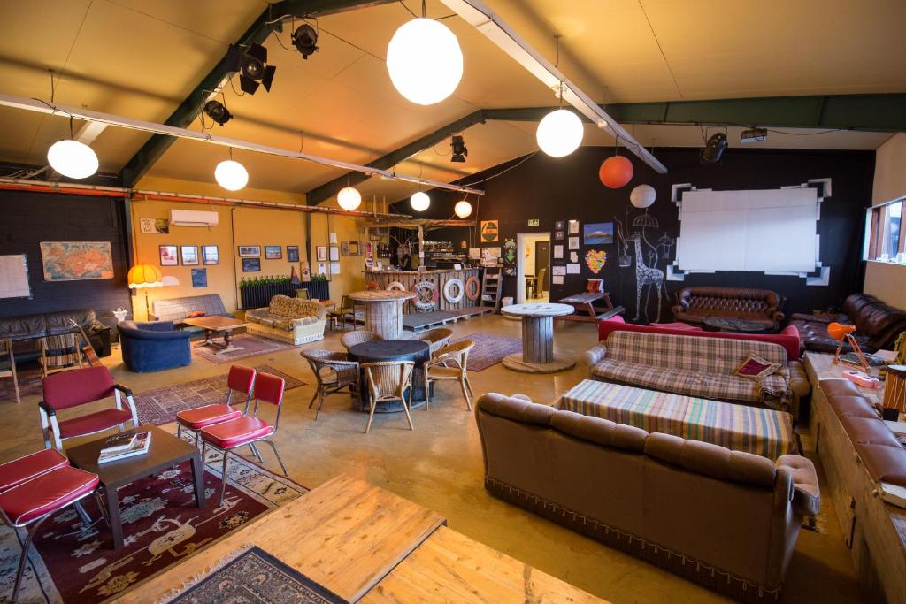 a living room with couches and tables and a screen at The Freezer Hostel & Culture Center in Hellissandur