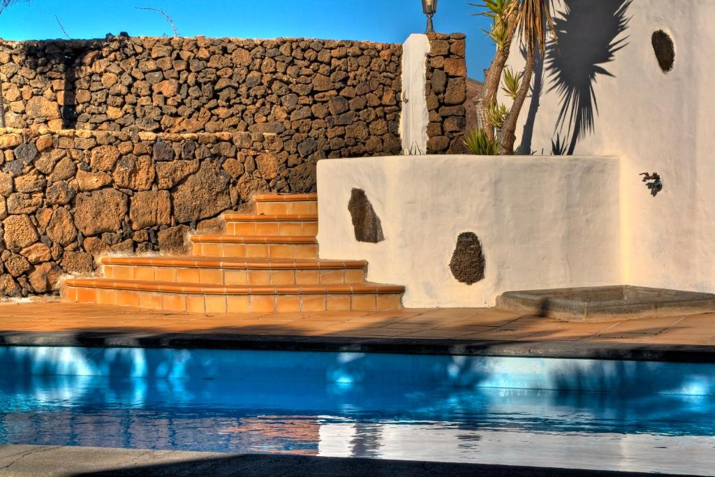 einen Pool mit einer Treppe neben einer Steinmauer in der Unterkunft Villa Timanfaya in Tinajo