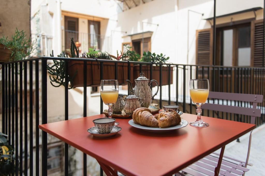 einem roten Tisch mit einem Teller mit Essen und Gläsern Orangensaft in der Unterkunft B&B Malvasia in Palermo