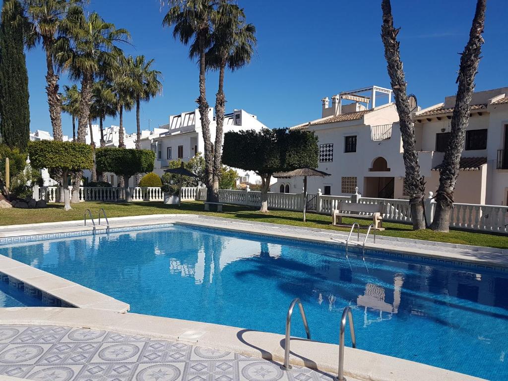 a swimming pool in front of a house with palm trees at Apartment Quesada in Ciudad Quesada