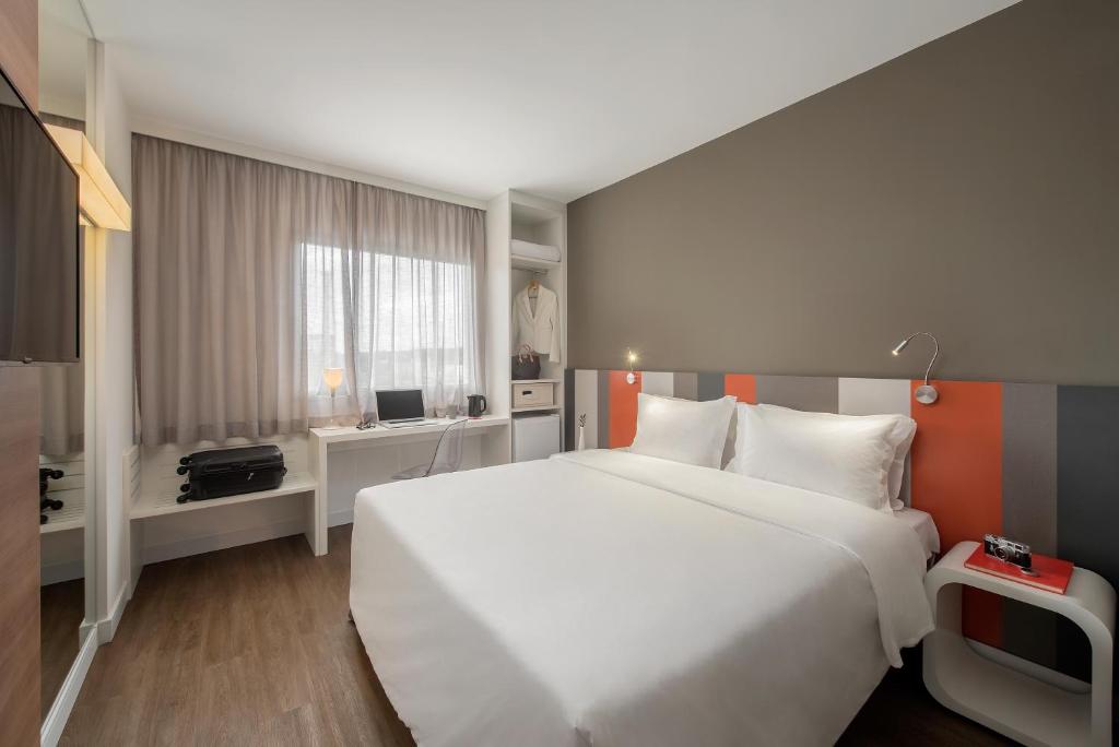 a bedroom with a large white bed and a window at Intercity Bauru in Bauru