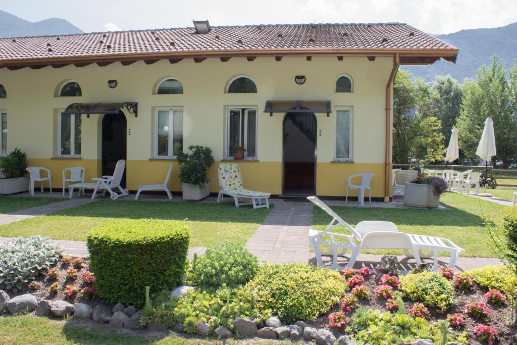 a yellow house with chairs and a garden at Casa Ornella in Ponte Caffaro