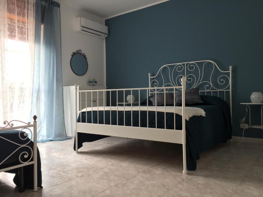 1 dormitorio con cama blanca y pared azul en La casa del Professore, en Tortora