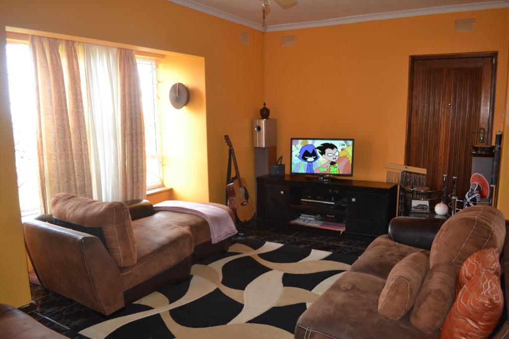 sala de estar con sofá y TV de pantalla plana en Mkhumbane Backpackers en Durban