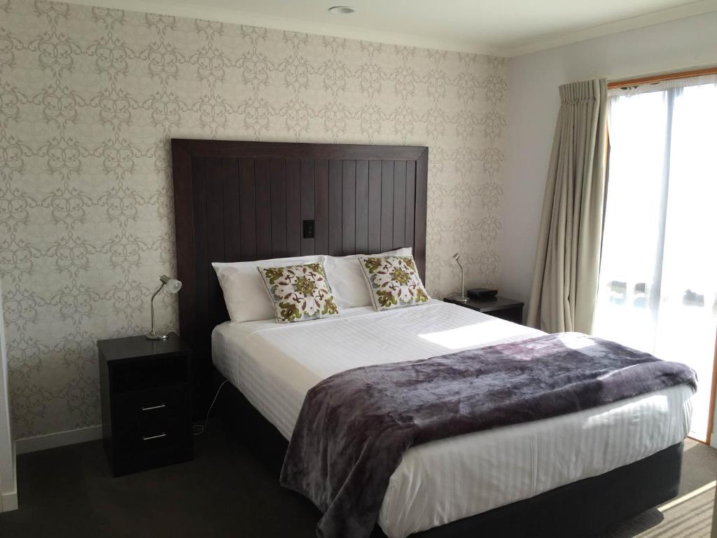 Un dormitorio con una cama grande y una ventana en Bethlehem Motor Inn and Conference Centre en Tauranga
