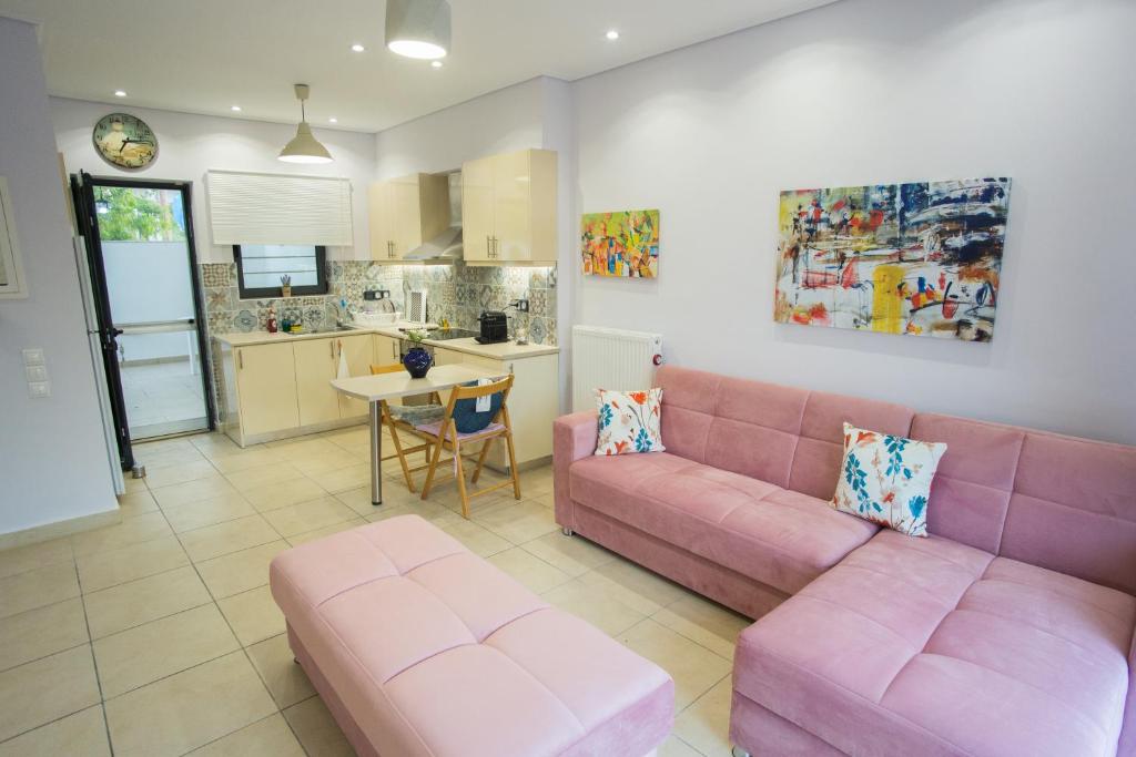 a living room with a pink couch and a kitchen at Porto Rafti view by Akroploro in Porto Rafti