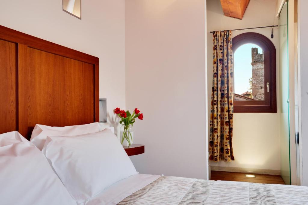 um quarto com uma cama branca e um vaso de flores em Hotel Due Mori em Marostica