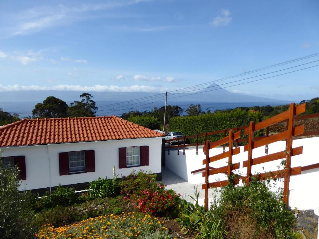 ein weißes Haus mit rotem Dach und einem Zaun in der Unterkunft Azorean Cottage São Jorge in Cais da Urzelina