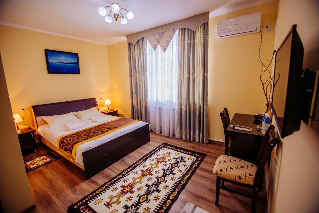 a bedroom with a bed and a table and a chair at Asman Guest House in Osh