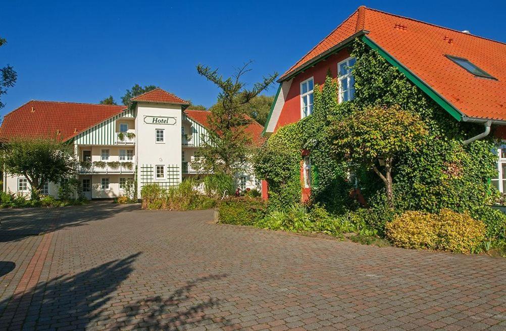 a building on a brick road next to a house at Landgasthof & Hotel Jagdhof in Stralsund