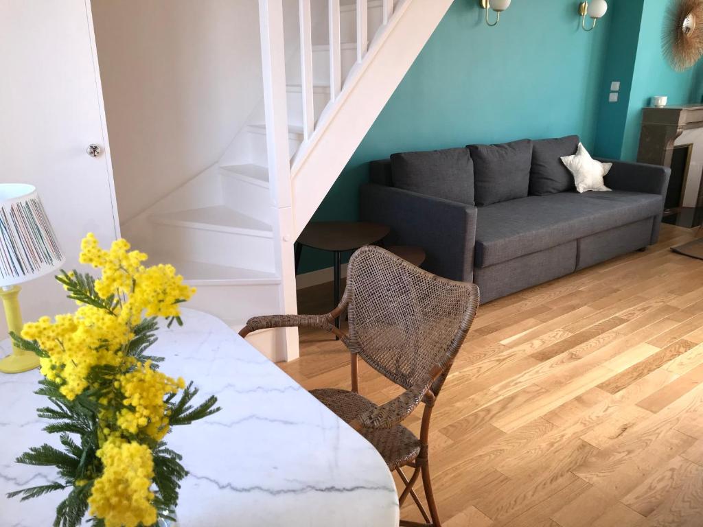 ein Wohnzimmer mit einem Sofa und einem Tisch mit gelben Blumen in der Unterkunft Deauville Triangle d OR in Deauville