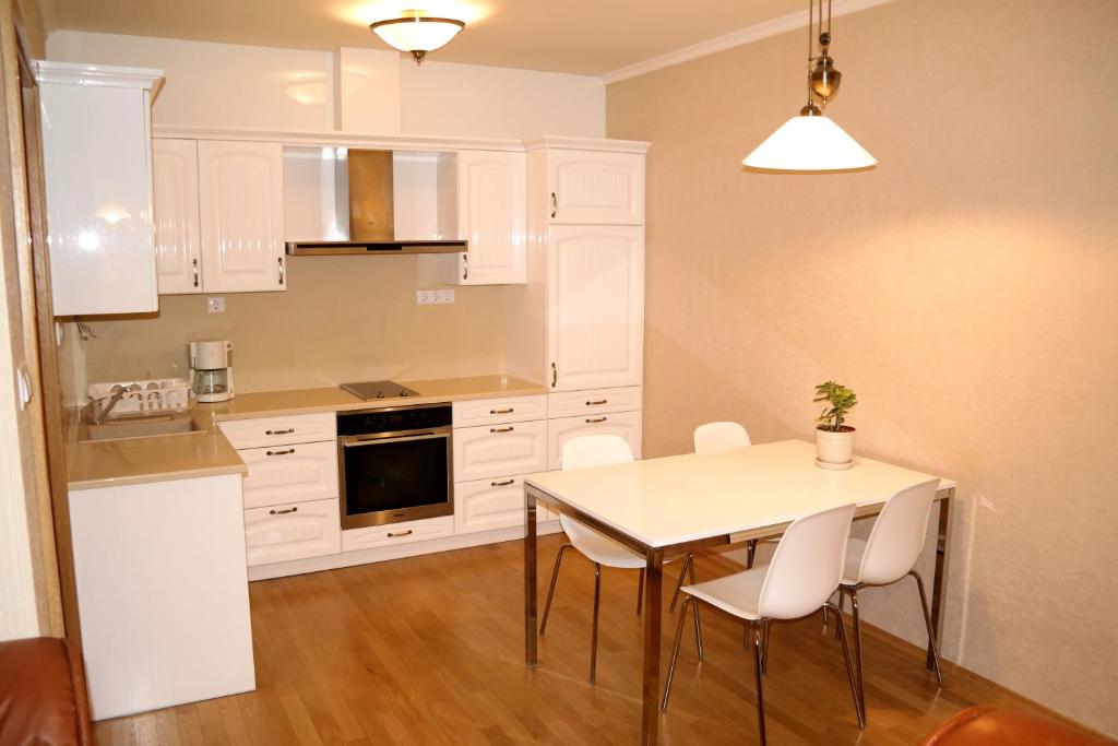 Centrum Apartman with Free Parking في جيور: مطبخ مع دواليب بيضاء وطاولة وكراسي