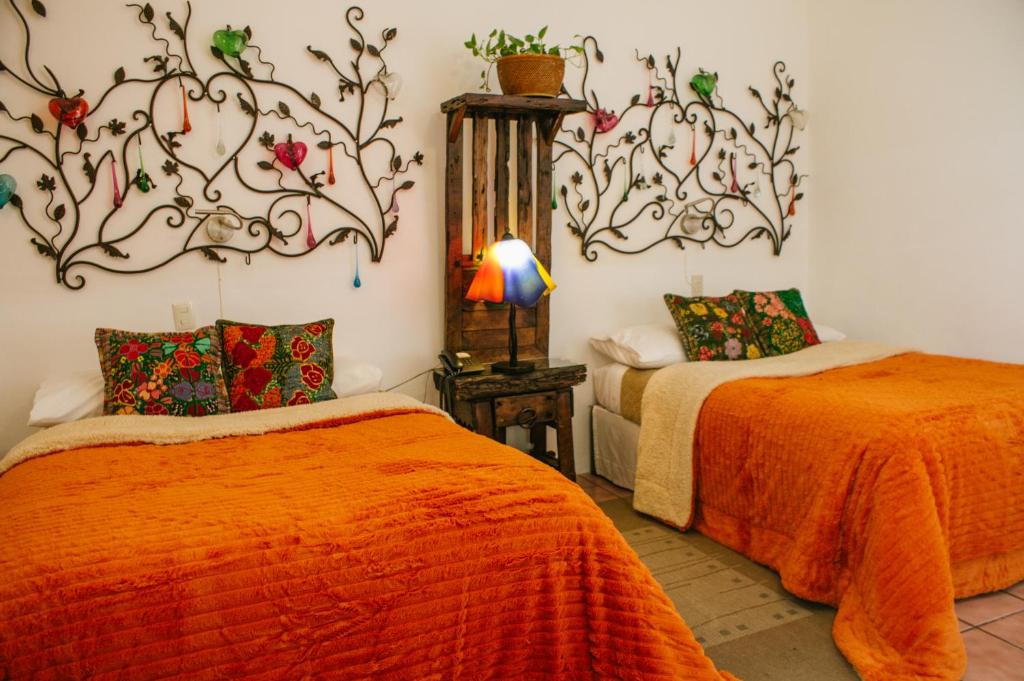 1 dormitorio con 2 camas con edredones de color naranja en La Casona de Tete, en Lagos de Moreno