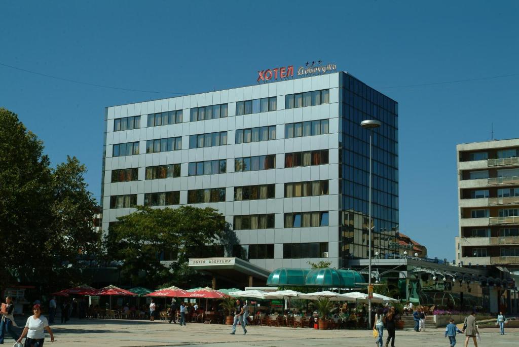 a tall building with people walking in front of it at Hotel Dobrudja in Dobrich