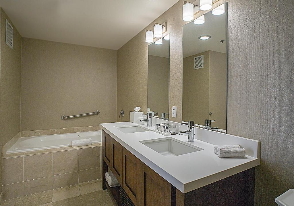 een badkamer met een wastafel, een spiegel en een bad bij Grand Hotel in Sunnyvale