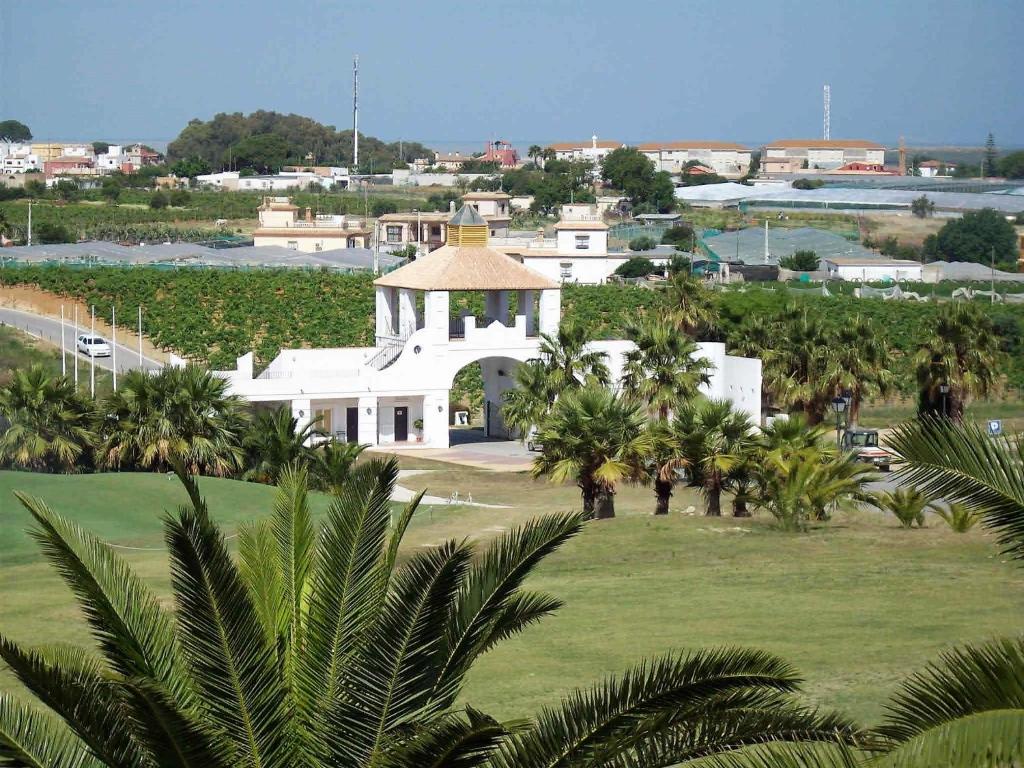 a white building with a gazebo in a field of palm trees at Cadiz Golf in Sanlúcar de Barrameda