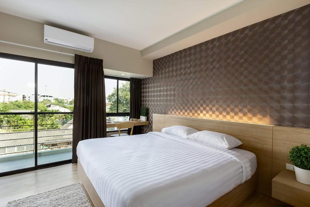 - une chambre avec un lit blanc et une grande fenêtre dans l'établissement @S115 Residence, à Samutprakarn