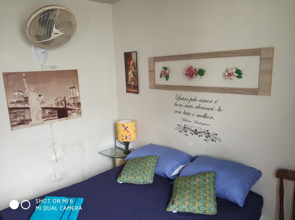een slaapkamer met een bed met blauwe kussens en foto's aan de muur bij Ap. do LeoSan in João Pessoa