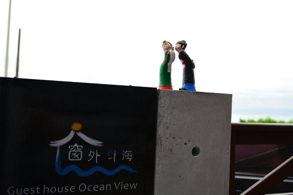 two figurines of two people standing on top of a sign at 窗外的海 - 海洋公園旁 in Yanliau