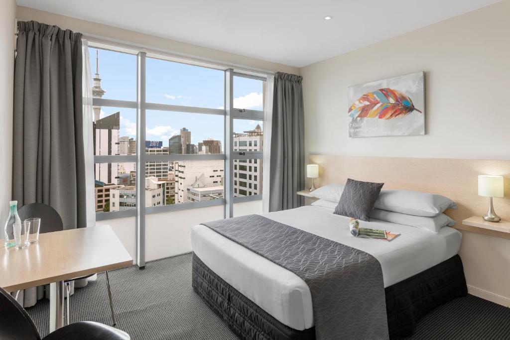 um quarto de hotel com uma cama e uma grande janela em Tetra Serviced Apartments by Castle em Auckland
