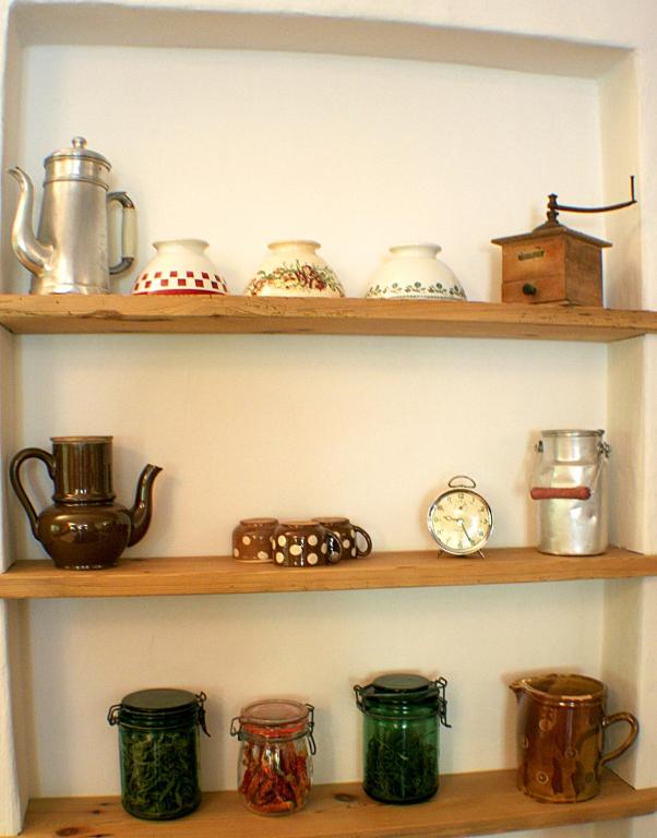 a shelf filled with pots and pans and a clock at Hotel Autantic in Bourg-Saint-Maurice