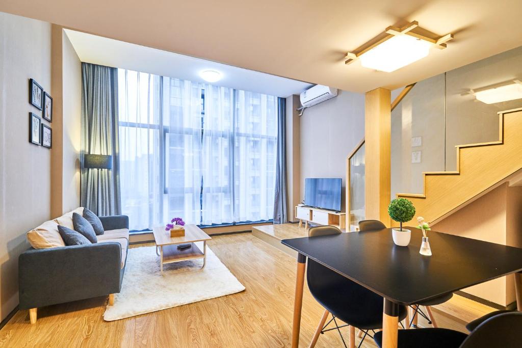 a living room with a table and a couch and a staircase at Plesant Daily Rental Apartment in Hangzhou