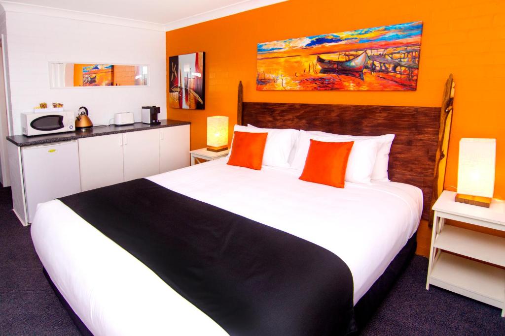 a bedroom with a large bed with orange walls at Crescent Motel Taree in Taree