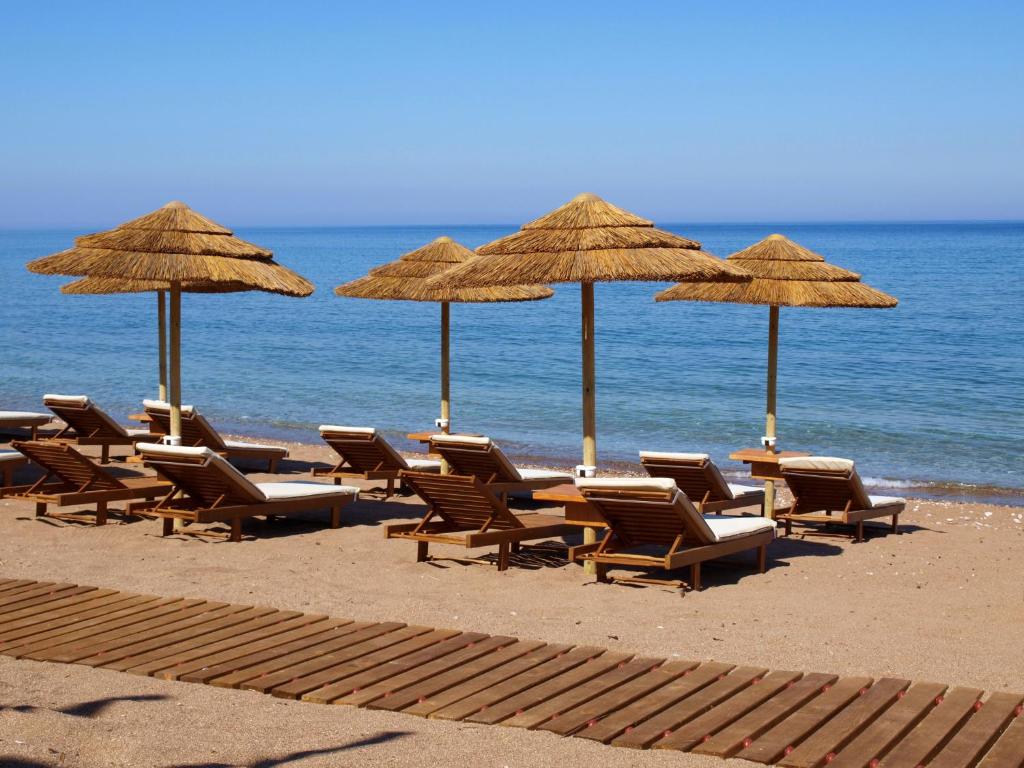 Messina Resort Hotel في كيباريسيا: مجموعة من الكراسي والمظلات على الشاطئ