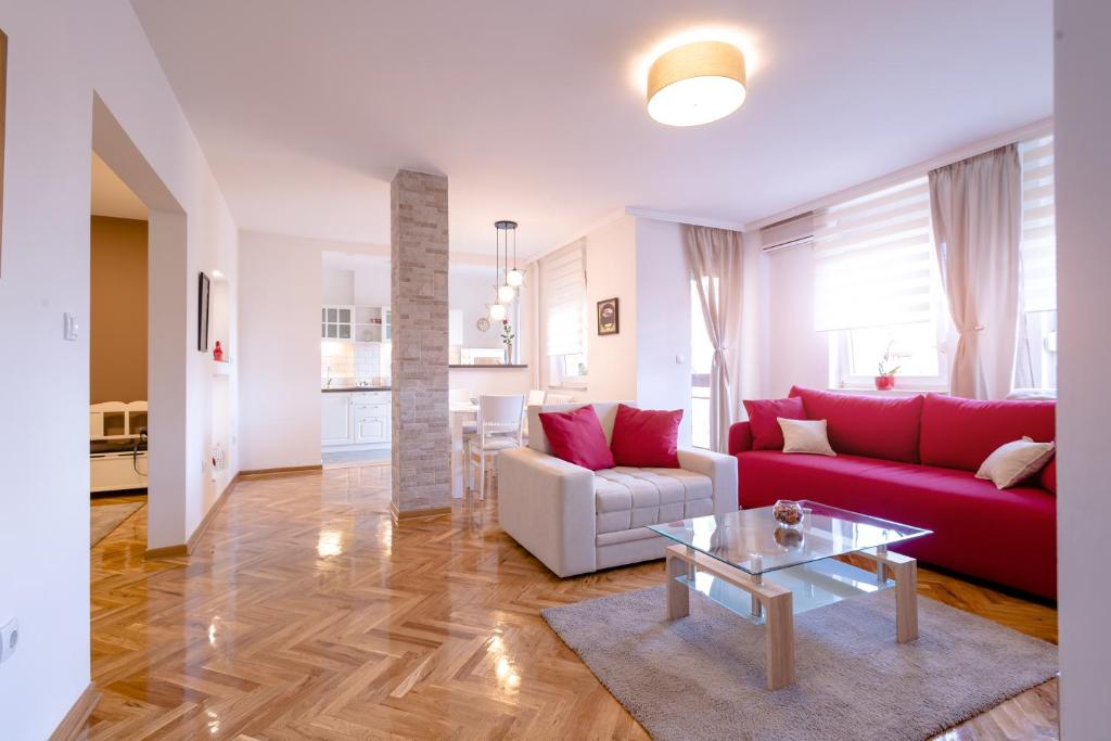uma sala de estar com um sofá vermelho e uma mesa em Apartman Arte em Novi Sad