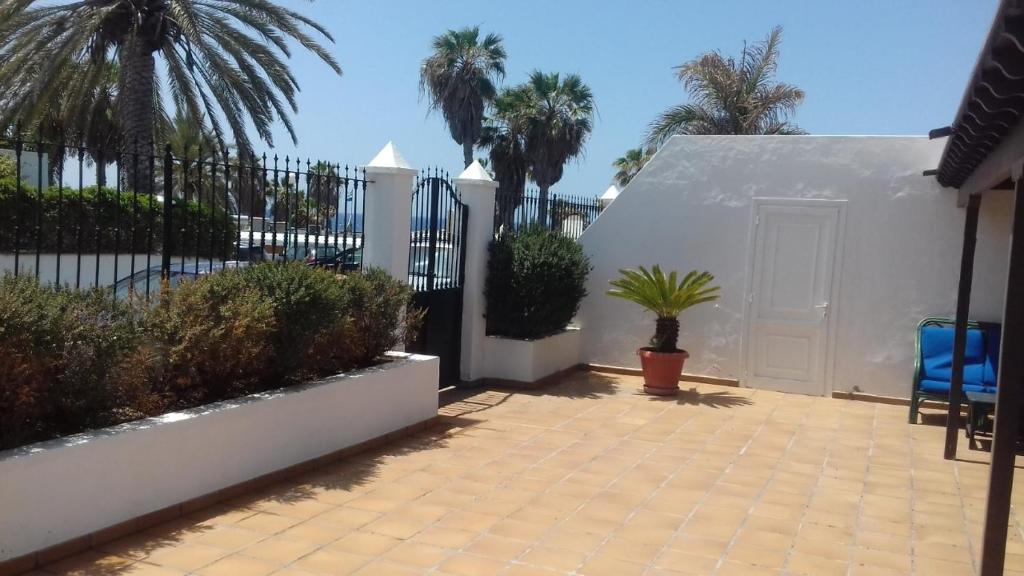 un patio con una valla blanca y palmeras en Casa Tiati, en Puerto del Carmen