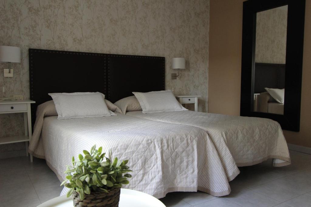una camera da letto con un grande letto con lenzuola bianche e uno specchio di Viviendas Uso Turístico Arzúa a Arzúa