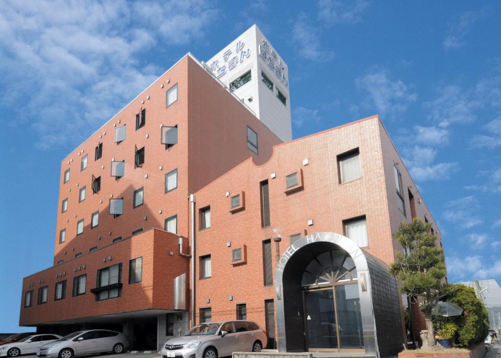 un edificio alto con coches estacionados frente a él en Hotel Hachiman, en Hachiman