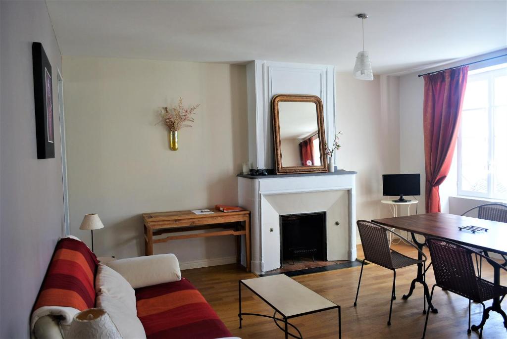 ein Wohnzimmer mit einem Sofa, einem Tisch und einem Spiegel in der Unterkunft Petite Roche gîtes centre-ville La Rochelle in La Rochelle