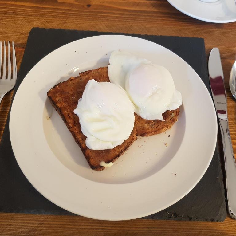un piatto bianco con un pezzo di pane tostato con panna montata di The Tables Guest House a Dunvegan