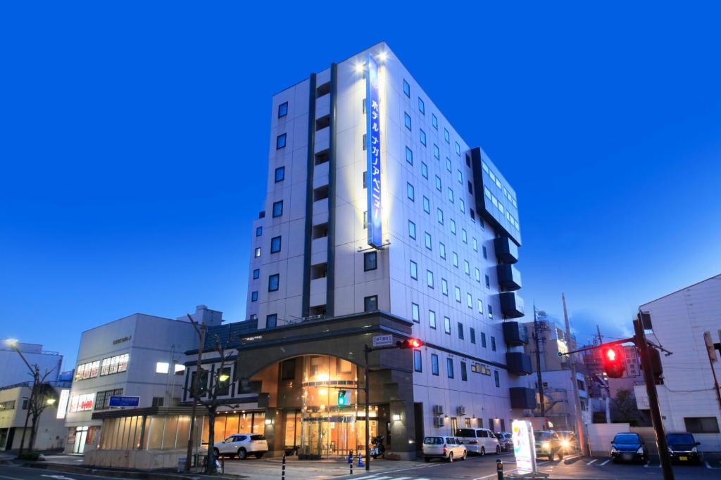 a tall white building on a city street at night at Hotel Nagano Avenue in Nagano