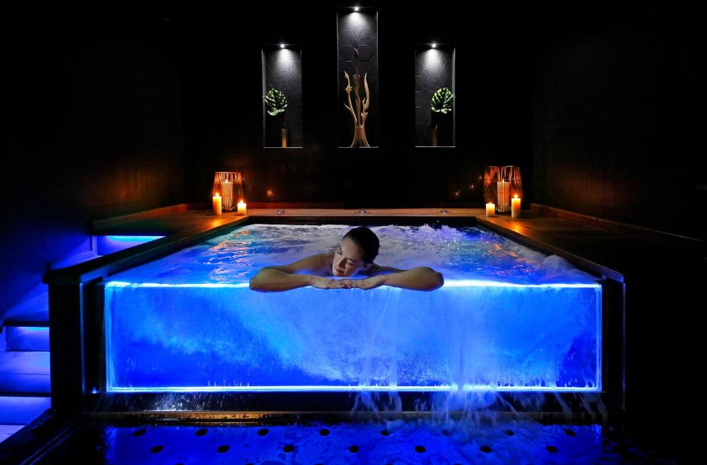 une femme se posant dans un bain à remous d'eau bleue dans l'établissement Negrecoste Hôtel & Spa, à Aix-en-Provence