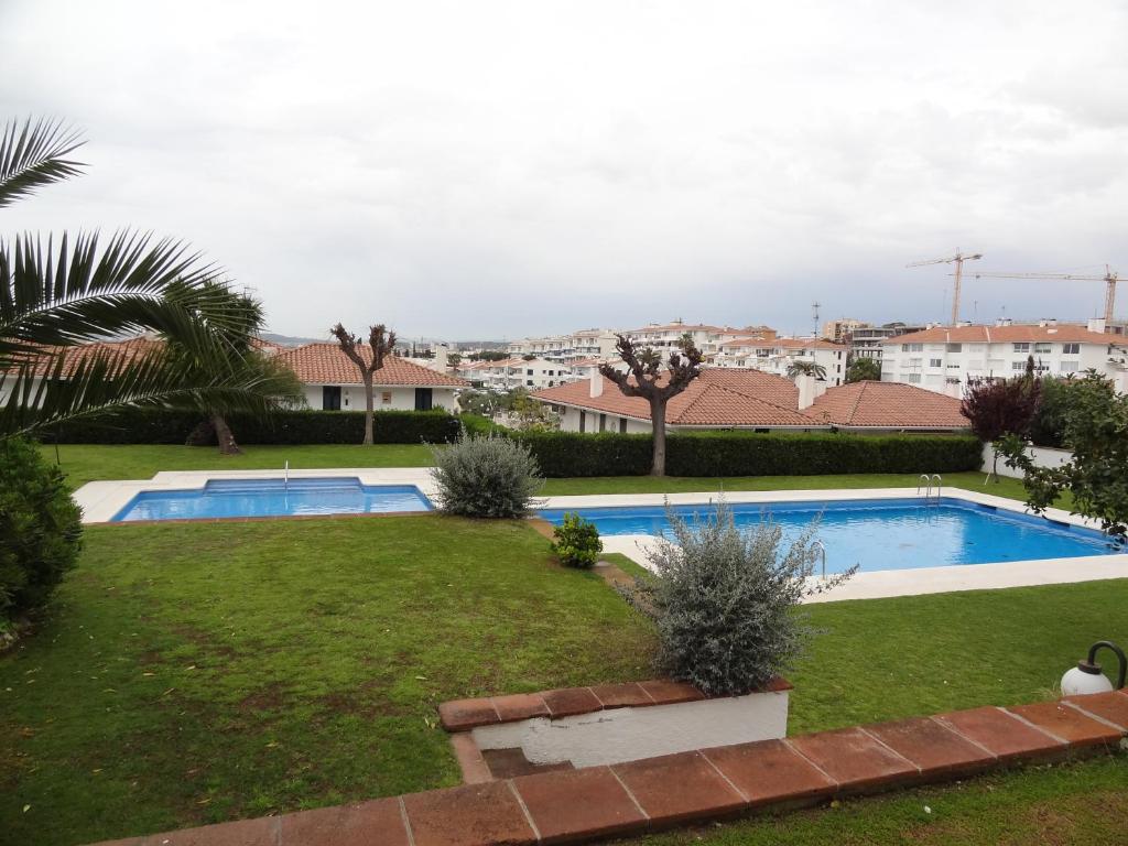 a large swimming pool in a yard with a grassy field at Ground Floor Sea View in Sitges