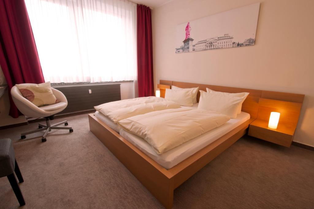 una camera con un letto e una sedia e una finestra di Hotel Credé a Kassel