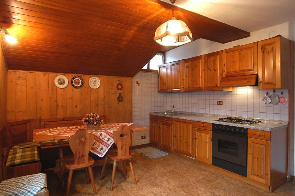 a kitchen with wooden cabinets and a table and a stove at Casa De Biasio PM in Falcade