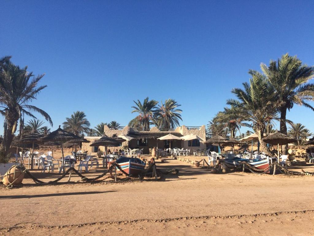 a beach with umbrellas and boats on the beach at Menzel Churasco Djerba in Aghīr