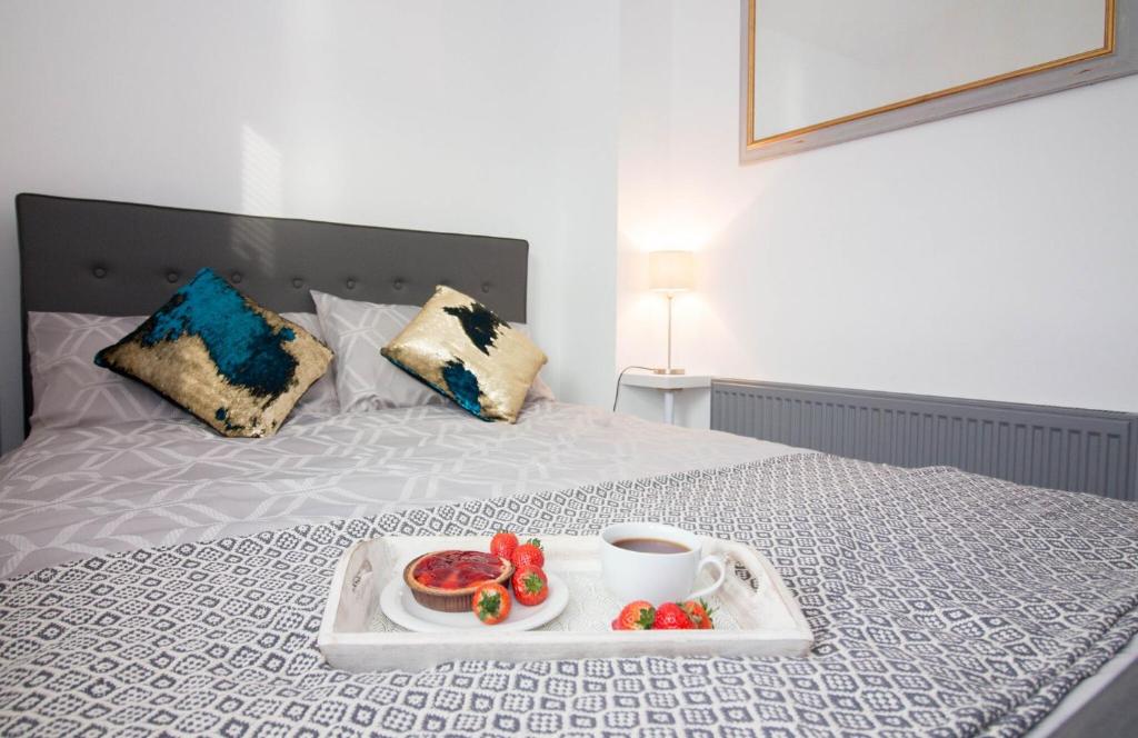 a tray of fruit and a cup of coffee on a bed at Magdalen Quarters in Exeter