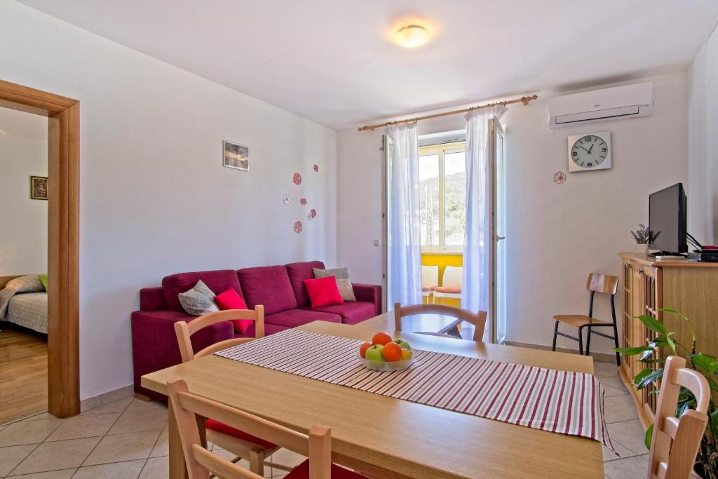 ein Wohnzimmer mit einem Tisch und einem roten Sofa in der Unterkunft Apartment Chiara Martinscica in Martinšćica