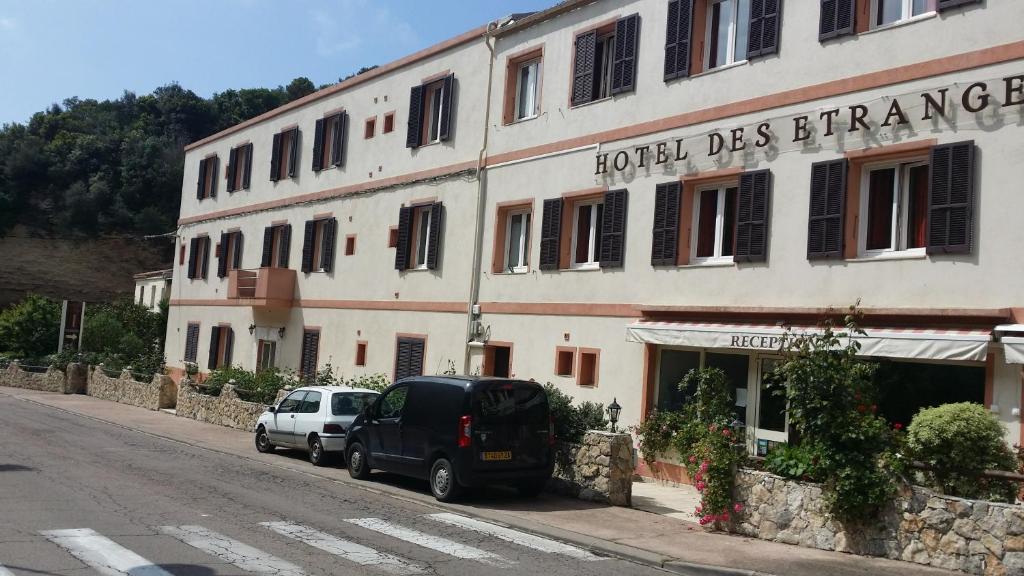 un hôtel d'entrée avec des voitures garées devant lui dans l'établissement Hotel des Etrangers, à Bonifacio